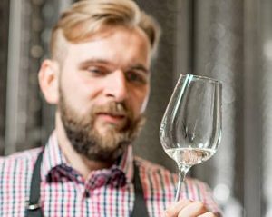 Waiter inspecting wine glass for hard water stains