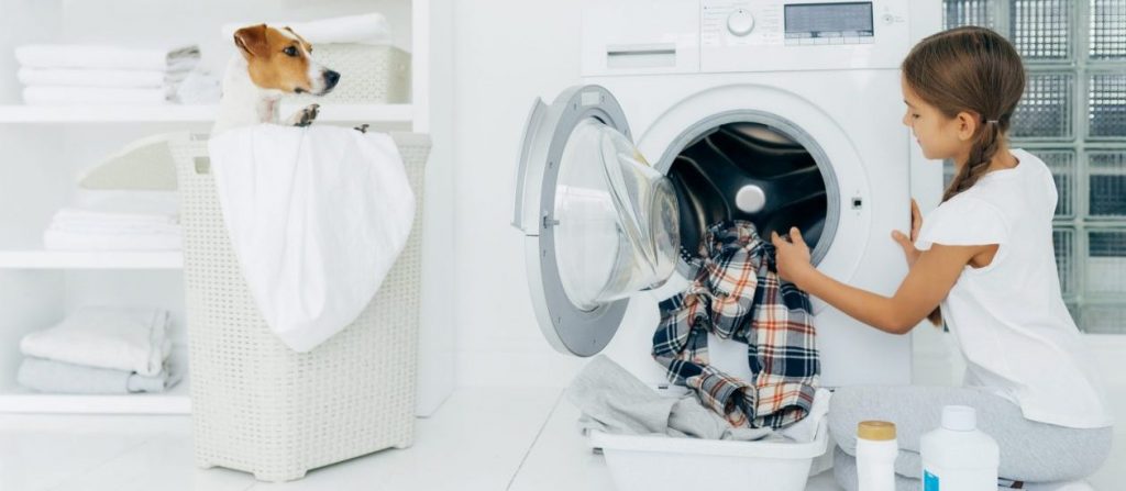 girl loading laundry in dryer