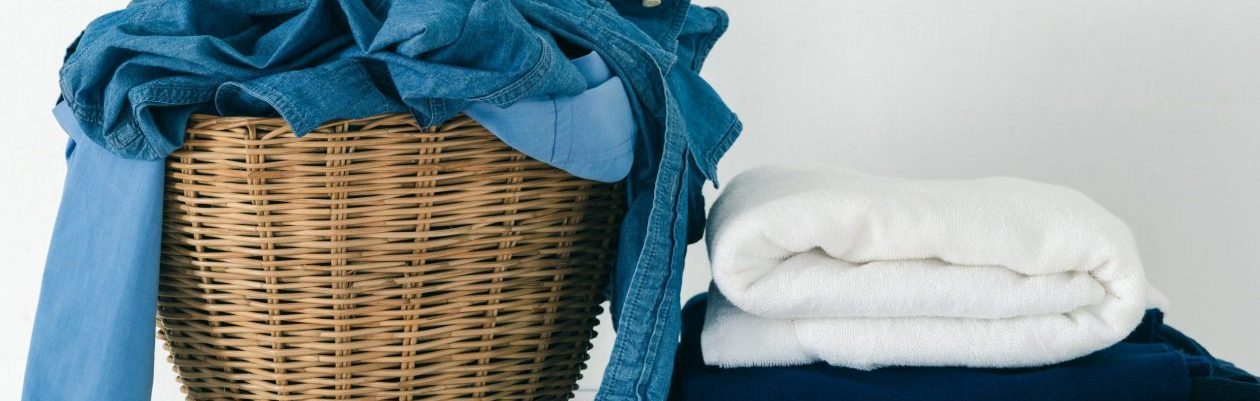 Close up clothes in basket and pile fabric on washing machine with white background.